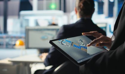 Photovoltaics factory specialist designs production lines in CAD app using tablet. Solar panels plant technician uses simulation software on device to optimize production layouts, camera A closeup